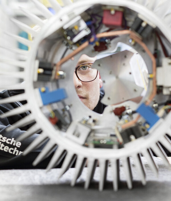 Servicetechniker schaut durch ein Bauteil einer Windenergiealage hindurch